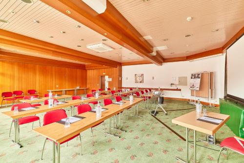 a classroom with wooden tables and red chairs at Mercure Hotel Bad Duerkheim An Den Salinen in Bad Dürkheim