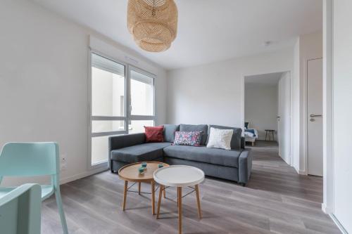 ein Wohnzimmer mit einem Sofa und einem Tisch in der Unterkunft NATHAN - Appartement proche gare arrivée 2424 in Le Mans