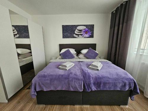 a bedroom with a purple bed with towels on it at Slunný byt v klidné části Hradce Králové - zahrada, parkování zdarma in Hradec Králové