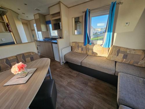a living room with a couch and a table at Caravan LEANNE in Meliden