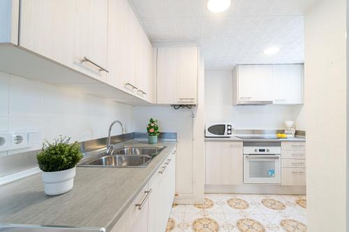 エンプリアブラバにあるBasic Comfort Apartment Port Emporda 0195の白いキャビネットとシンク付きのキッチン