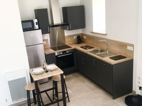 une cuisine avec des placards noirs et une petite table avec des tabourets dans l'établissement La p’tite Escale des Brias - L’escale des Brias, à Saint-Martin-Lacaussade