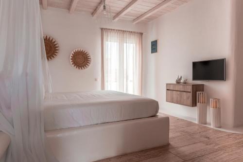 a white bedroom with a bed and a television at Senses Luxury Suites & Villas in Elia Beach