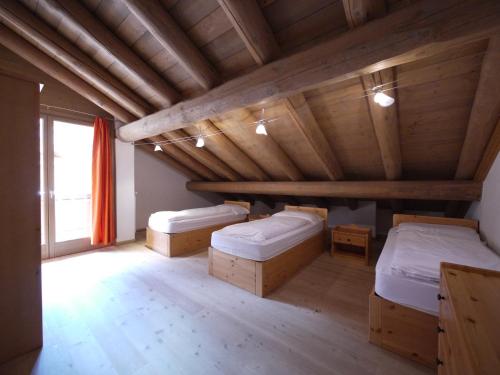 a room with two beds and a wooden ceiling at Appartamenti Home Service in Arabba