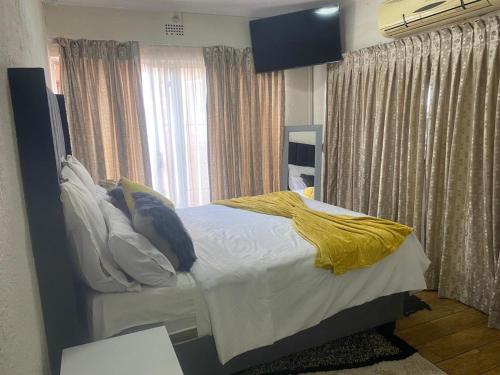 a bedroom with a bed with a yellow blanket on it at Golden Glory Manor in Roodepoort