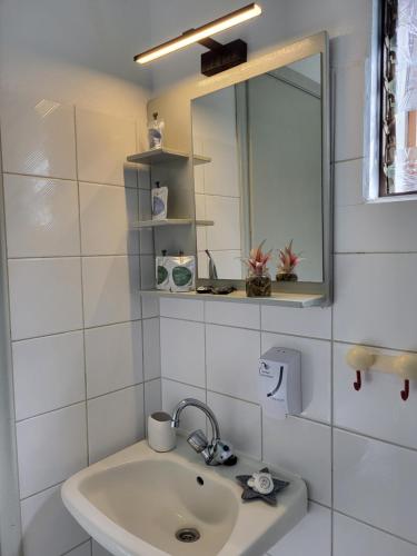 a white bathroom with a sink and a mirror at Aura Guesthouse in Kinira