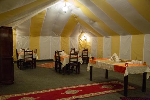 a dining room with tables and chairs in a tent at Erg Chebbi Desert Luxury Camp in Merzouga