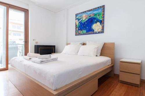 um quarto com uma grande cama branca com um quadro na parede em Riviera Retreat 3 Bedroom Voula Luxury Haven Apt em Atenas