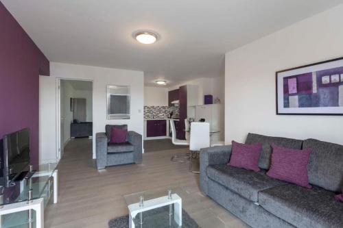 uma sala de estar com um sofá cinzento e almofadas roxas em SAV Apartments Clarence Street-Loughborough em Loughborough