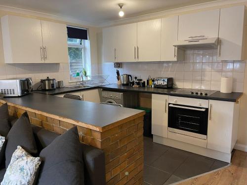 a kitchen with white cabinets and a black counter top at SAV 1 Bedroom Flat near Watford Town Centre in Watford