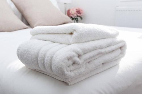 a pile of white towels sitting on a bed at SAV - 4 Bed Town House, Harrow in Harrow