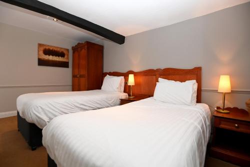 two beds in a hotel room with white sheets at Original White Hart, Ringwood by Marston's Inns in Ringwood