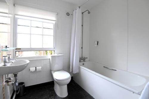 Baño blanco con aseo y lavamanos en Original White Hart, Ringwood by Marston's Inns en Ringwood