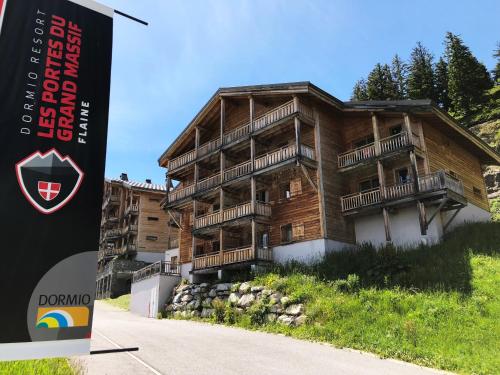 un bâtiment en bois avec un panneau en face de celui-ci dans l'établissement Dormio Resort Les Portes du Grand Massif, à Flaine