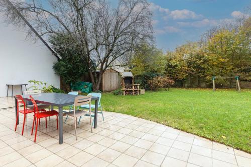 uma mesa e cadeiras num pátio com um quintal em Maison familiale avec jardin et garage em Beaucouzé