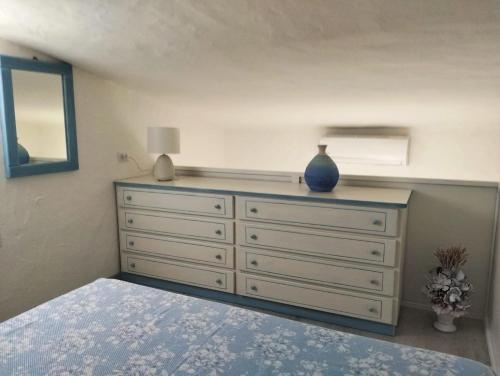 a bedroom with a dresser with a blue vase on it at Villetta Luna in San Teodoro