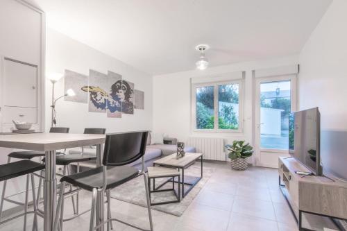 a living room with a table and chairs and a tv at L'URBAIN - Appartement proche gare in Saint-Nazaire