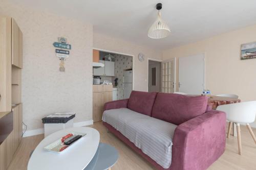 een woonkamer met een paarse bank en een tafel bij LE VINTAGE - Appartement proche plage in Saint-Nazaire