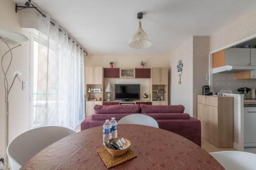uma sala de estar com uma mesa e um sofá roxo em LE VINTAGE - Appartement proche plage em Saint-Nazaire
