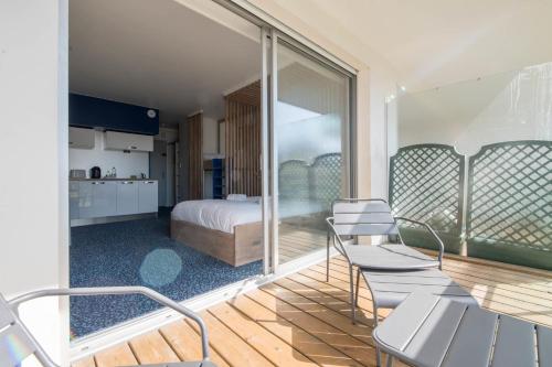 a bedroom with a bed and a balcony with chairs at LE DESIGN - Appartement vers la gare in La Baule