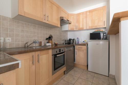 una cucina con armadi in legno e frigorifero bianco di LE NID - Appartement centre La Baule a La Baule