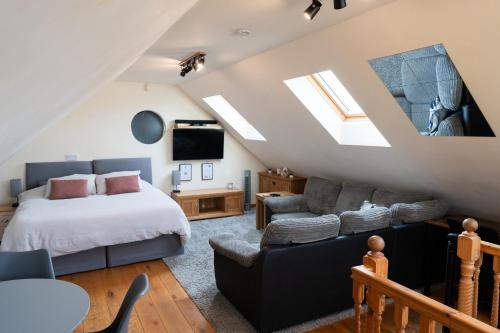 Silverwood Loft في تيلفورد: غرفة نوم في العلية مع سرير وأريكة