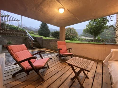 2 chaises et une table sur une terrasse en bois dans l'établissement Casa estilo rural con jardín entre playa y montaña, à Caravia