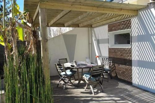 d'une terrasse avec une table et des chaises sous une pergola. dans l'établissement Maison familiale entre parc et plage, à Saint-Nazaire