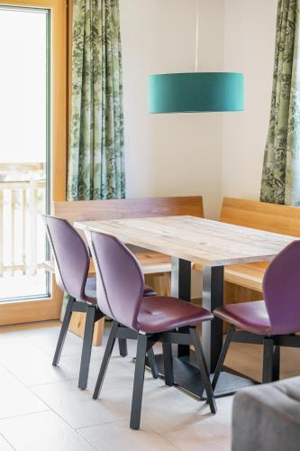a dining room with a wooden table and purple chairs at Lisas Schröcken in Schröcken