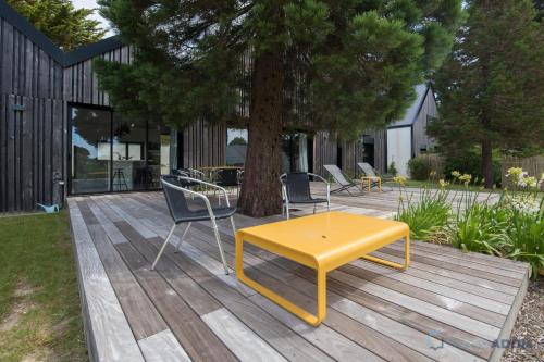 ein gelber Tisch und Stühle auf einer Holzterrasse in der Unterkunft Sekoya Villa proche plage et golf in Pornic