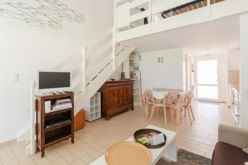 a living room with a tv and a staircase at Maison en résidence proche du vieux port in Pornic