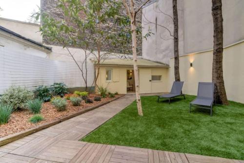 - un jardin avec 2 chaises dans la pelouse dans l'établissement Jardin - Jacuzzi - chambres en suite, à Paris