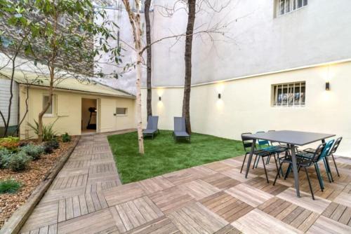 un patio avec une table et des chaises dans une cour dans l'établissement Jardin - Jacuzzi - chambres en suite, à Paris