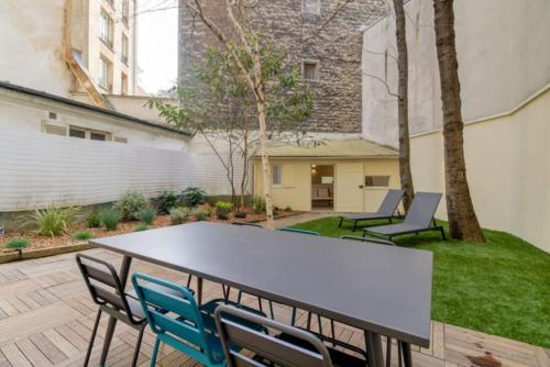 un patio avec une table et des chaises dans une cour dans l'établissement Jardin - Jacuzzi - chambres en suite, à Paris