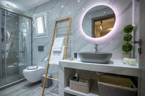 La salle de bains est pourvue d'un lavabo, de toilettes et d'un miroir. dans l'établissement George Luxury Beach House, à Aiándion