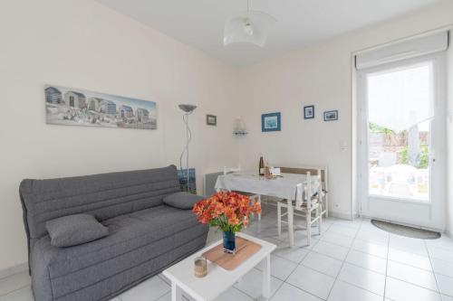 een woonkamer met een bank en een tafel met bloemen bij Birochère Maison lumineuse avec jardin in Pornic