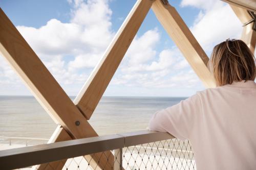 a woman looking out at the ocean from a balcony at C-Hotels Silt in Middelkerke