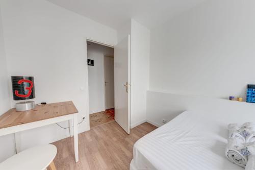 biała sypialnia z łóżkiem i biurkiem w obiekcie Grand app lumineux proche défense w mieście Courbevoie