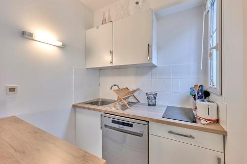 a small kitchen with white cabinets and a sink at L'Augustine - Appartement dans le 15e in Paris