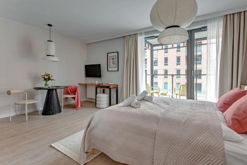 a white bedroom with a large bed and a table at Scala Apartments by Blue Mandarin in Gdańsk