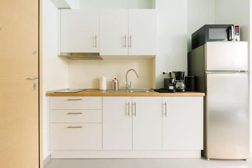 a kitchen with white cabinets and a refrigerator at Snug studio apartment with shared garden IV in Athens