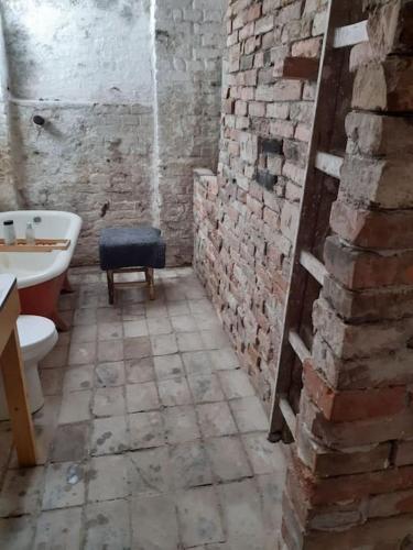 a bathroom with a toilet and a sink and a brick wall at Central Industrial Souterrain in Vienna