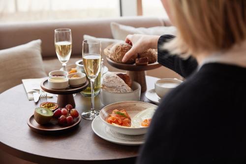 a woman sitting at a table with food and glasses of wine at C-Hotels Silt in Middelkerke