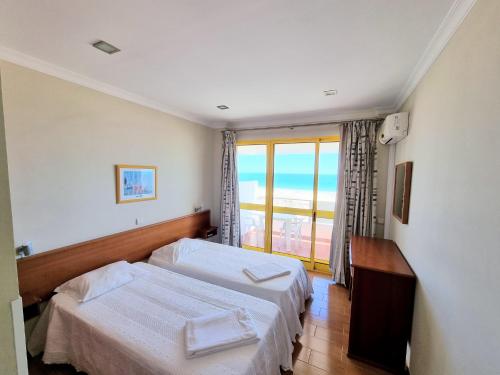 a hotel room with two beds and a window at Vista Oceânica Paradise in Monte Gordo