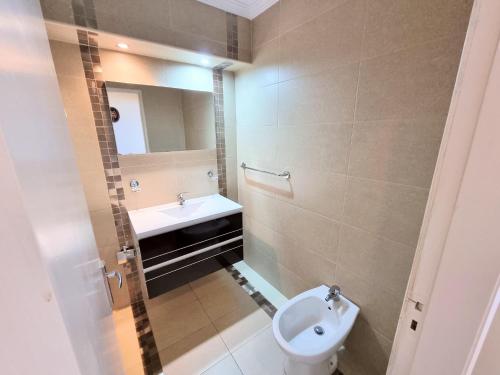 a bathroom with a white toilet and a sink at Vista Oceânica Paradise in Monte Gordo