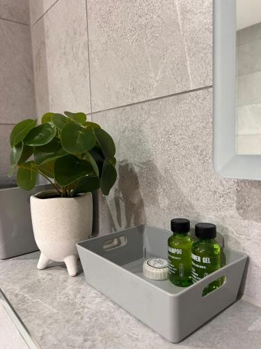 - un lavabo dans la salle de bains avec 2 bouteilles vertes dans l'établissement Cosy Suite in Shirley, à Solihull