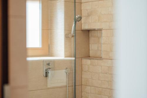 a shower with a glass door and a window at Sándor Panzió 2 in Praid