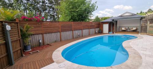 a swimming pool in a backyard with a wooden fence at Guest Studio in Campbelltown 