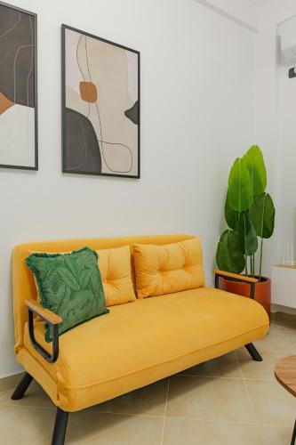a yellow couch in a living room with paintings at Sunny Apts in Sarandë