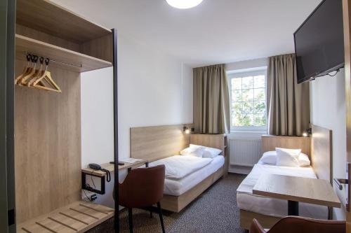a hotel room with two beds and a desk at Hotel Avion in Prague
